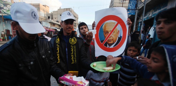 Palestinos celebram a morte do ex-primeiro-ministro israelense Ariel Sharon (que aparece na imagem do cartaz), em Khan Youni, ao sul da faixa de Gaza