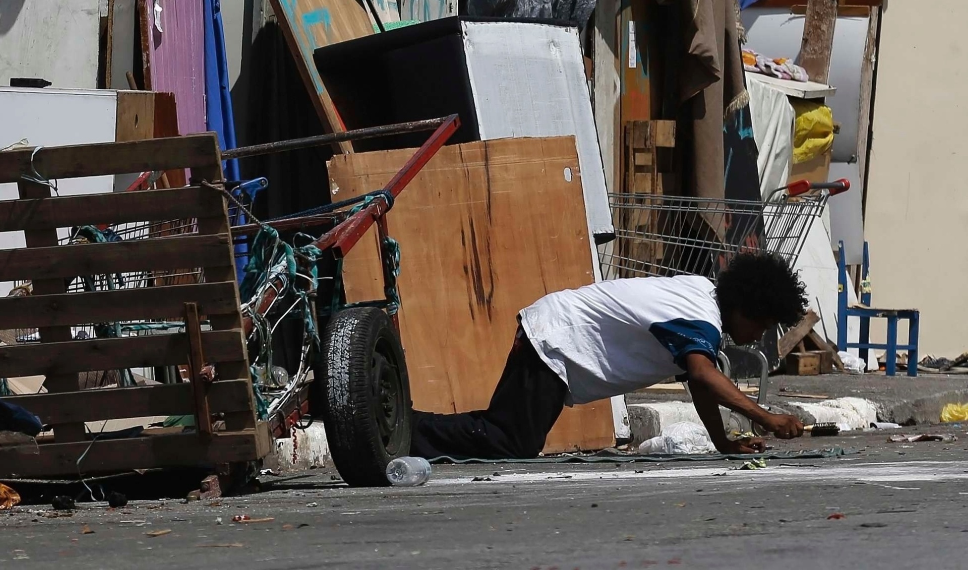 14.jan.2014 - Um homem limpa o chão com uma escova em frente ao seu barraco, no bairro da Luz, região central de São Paulo, em local conhecido como Cracolândia, nesta terça-feira (14). Nesta quarta-feira (15), mais de 180 barracos erguidos nas calçadas da alameda Dino Bueno com a rua Helvétia deverão ser desmontados pelos próprios usuários, como está previsto no Programa Operação Trabalho da prefeitura, em parceria com a ONG União Social Brasil Gigante. O projeto prevê o pagamento de R$ 15 por dia aos usuários em troca de quatro horas de trabalho, mais duas horas de requalificação profissional - Nacho Doce/Reuters