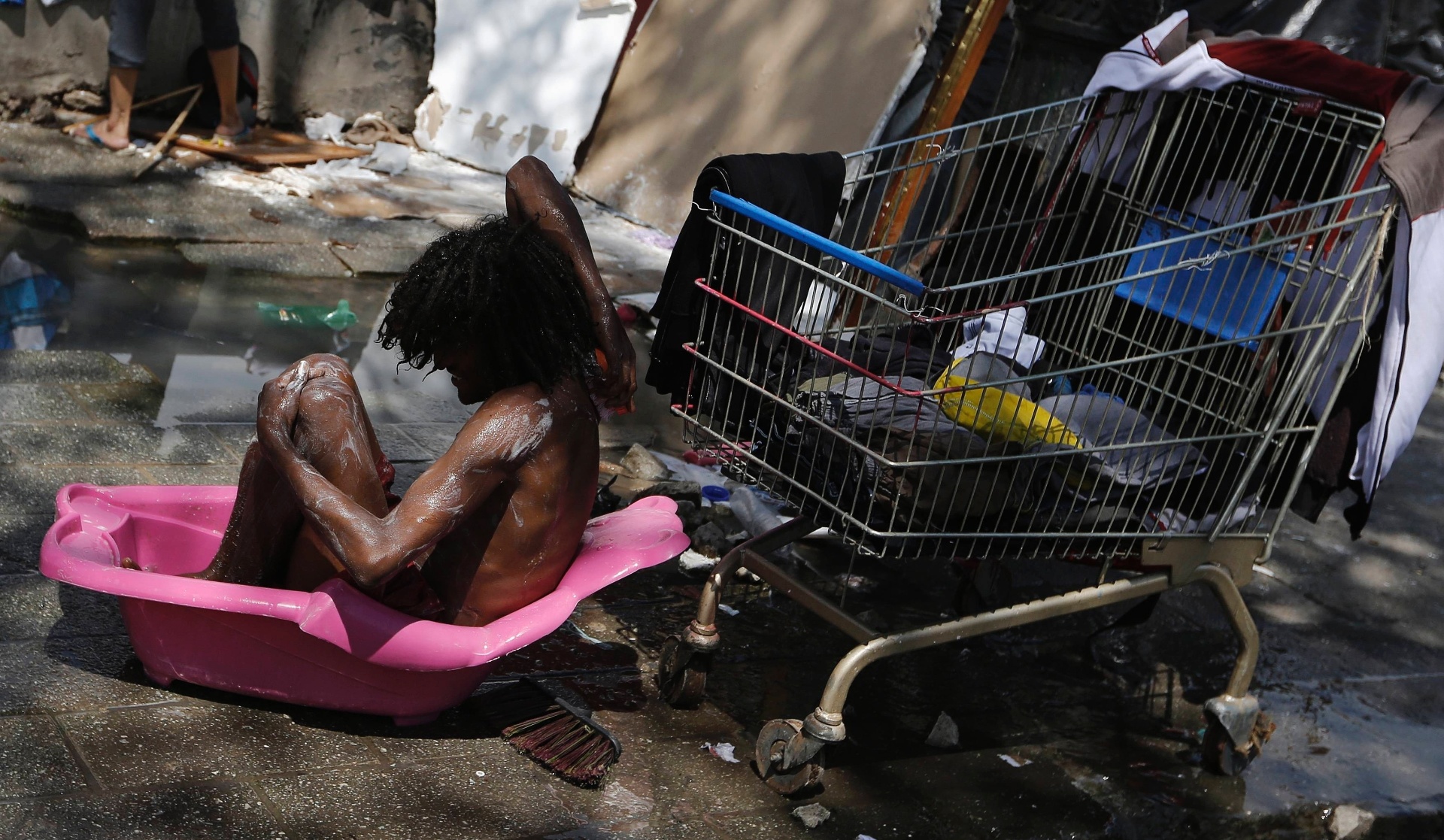 14.jan.2014 - Um homem toma banho dentro de uma banheira de criança em frente a um barraco, no bairro da Luz, região central de São Paulo, em local conhecido como Cracolândia.A prefeitura iniciou nesta terça-feira (14) a retirada barracos erguidos na calçada da alameda Dino Bueno. Os sem-teto deixaram o local pacificamente e estão sendo levados para um hotel na esquina da Dino Bueno com a rua Helvétia. A operação estava marcada para amanhã, mas foi antecipada porque, sabendo que seriam removidos, os próprios sem-teto iniciaram o desmonte dos barracos nesta manhã. A ação faz parte do programa Operação Trabalho, que prevê o pagamento de R$ 15 por dia aos usuários em troca de quatro horas de trabalho, mais duas horas de requalificação profissional - Nacho Doce/Reuters