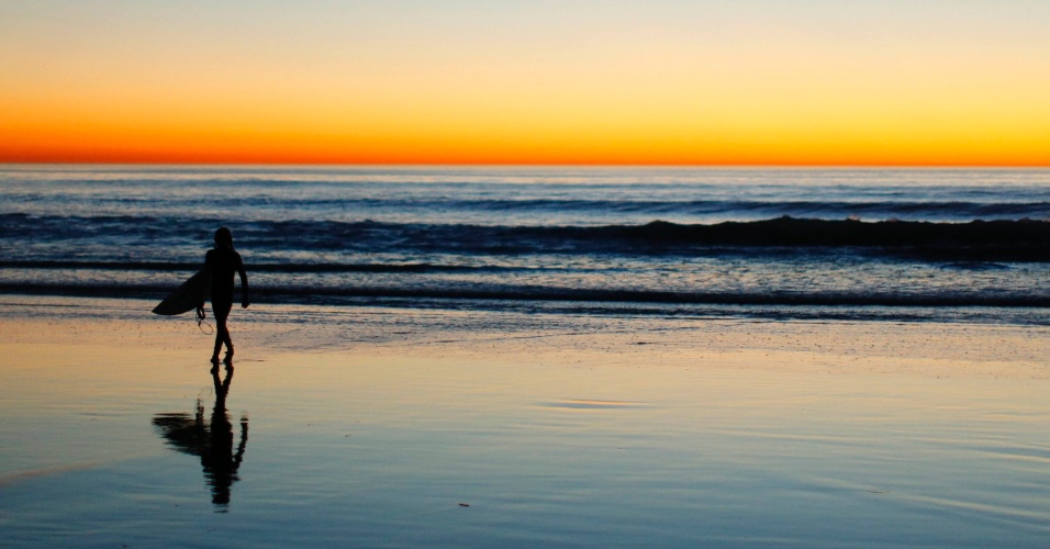 16.jan.2014 - Surfista solitário  deixa o mar com o pôr do sol em Leucadia, na Califórnia, nos EUA