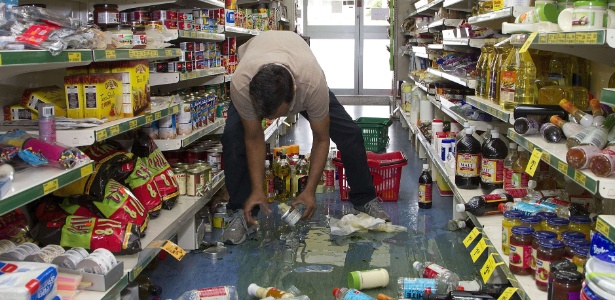 Proprietário de mercado na cidade de Eketahuna recolhe garrafas que foram ao chão por causa do terremoto - Marty Melville/AFP