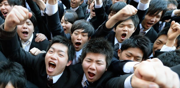 Estudantes universitários gritam enquanto levantam os braços no início da cerimônia que marca a caça anual por trabalho, em Tóquio, no Japão. A foto é de 2014 - Toru Yamanaka/AFP