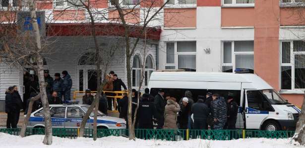 Membros do Ministério do Interior e outras autoridades se reúnem fora de uma escola em Moscou, onde um aluno sequestrou 24 alunos e um professor