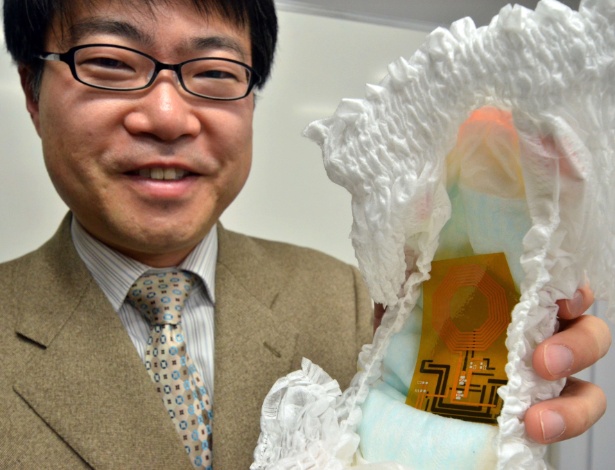 Takao Someya, pesquisador da Universidade de Tóquio, segura uma fralda e o sensor orgânico flexível  - Yoshikazu Tsuno/AFP