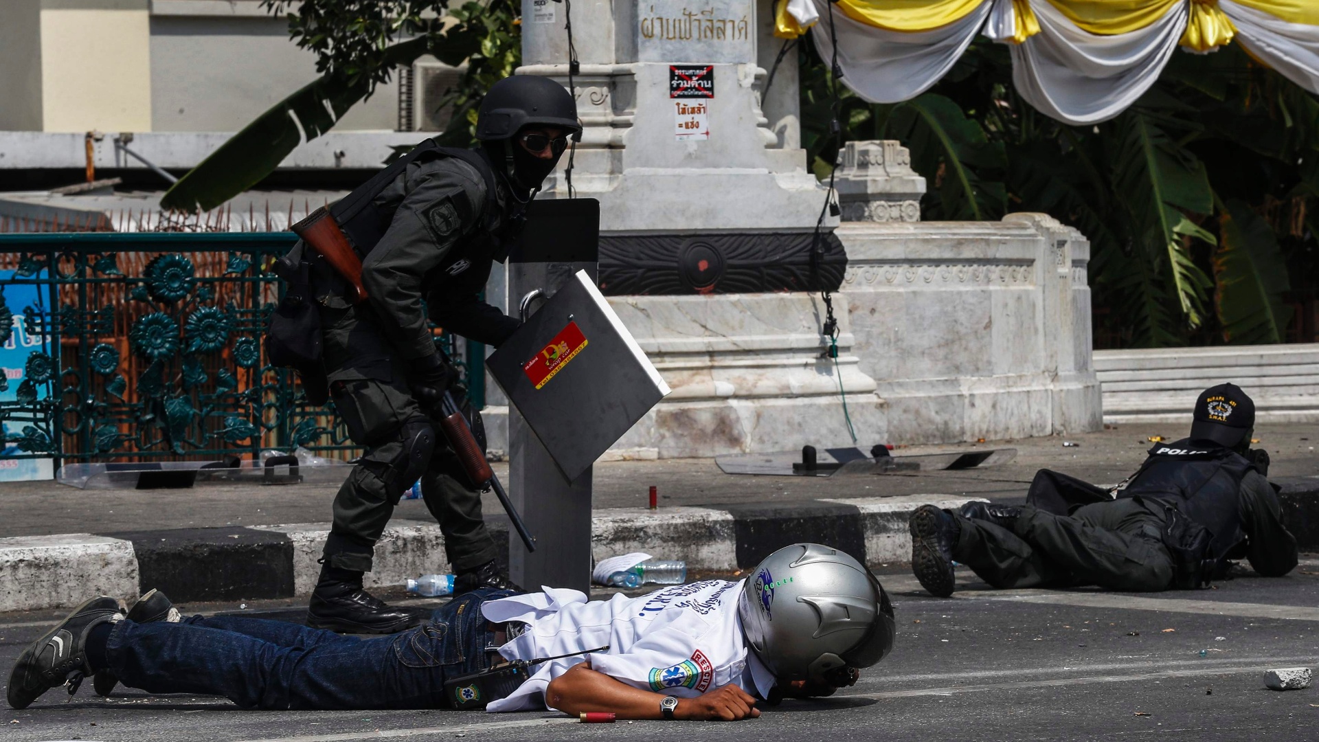 Policiais tailandeses se abrigam durante confrontos com manifestantes perto do palácio do governo em Bangcoc