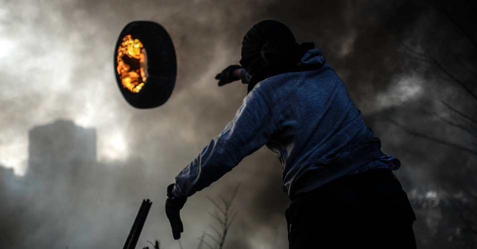 21.fev.2014 - Manifestante antigoverno lança um pneu em chamas na construção de uma barricada em Kiev, na Ucrânia