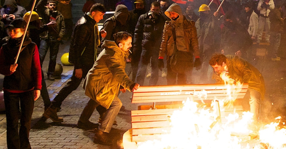 25.fev.2014 - Manifestantes colocam fogo em um banco em confronto com policiais durante manifestação em Istambul, nesta terça-feira (25). A polícia lançou canhões de água e gás lacrimogêneo para dispersar os milhares de manifestantes que gritavam 