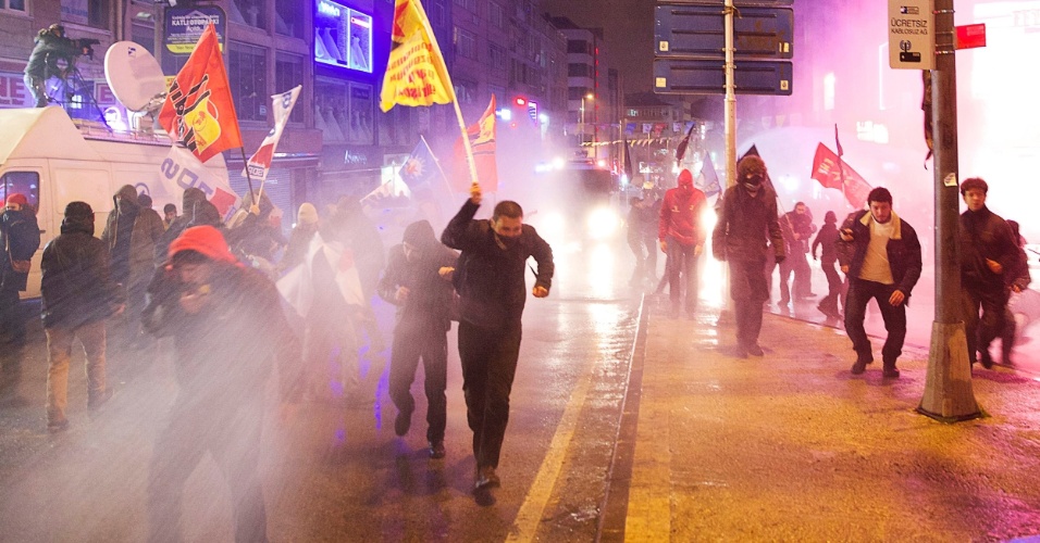 25.fev.2014 - Manifestantes correm para fugir do canhão de água e bombas de gás lacrimogêneo usados pela policia durante manifestação contra o primeiro-ministro da Turquia, Tayyip Erdogan, em Istambul, nesta terça-feira (25). Milhares de manifestantes que gritavam 