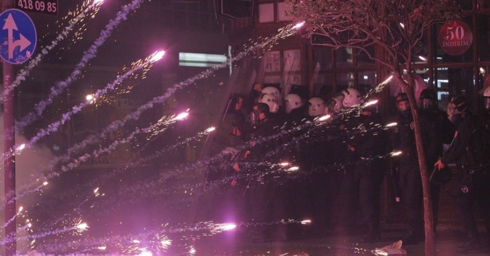 25.fev.2014 - Policiais se protegem de fogos de artifício atirados por manifestantes durante manifestação em Istambul, nesta terça-feira (25). A polícia lançou canhões de água e gás lacrimogêneo para dispersar os milhares de manifestantes que gritavam 