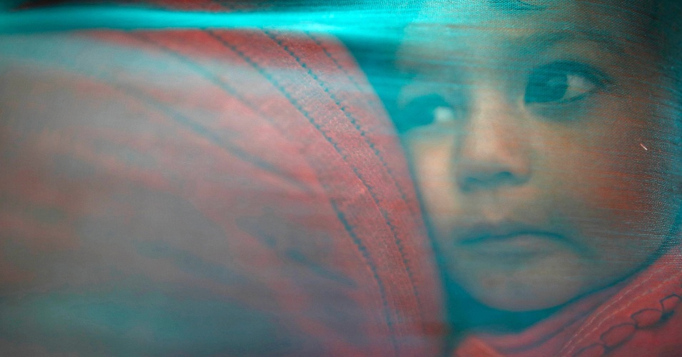 6.mar.2014 - Menino coberto com um xale, no colo de sua mãe, chega para fazer exames médicos gratuitos, durante um evento organizado pela Anistia Internacional em Nuwakot, no Nepal