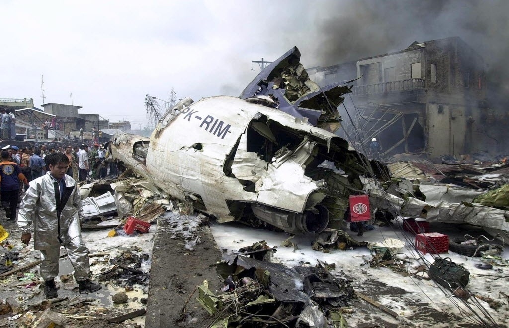 5.set.2005 - Bombeiro caminha sobre destroços do Boeing 737-200 que caiu sobre casas em um bairro residencial de Medan, no norte da Indonésia. Já chega a 147 o número de mortos no acidente do avião da Mandala Airlines, que transportava 111 passageiros e cinco tripulantes. Segundo as autoridades, pelo menos 100 pessoas a bordo morreram. As vítimas que estavam na rua e nas casas atingidas pelo avião chegam a 47 - AFP