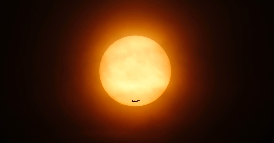 11.mar.2014 - Avião de passageiros voa na frente do sol em Xangai, na China