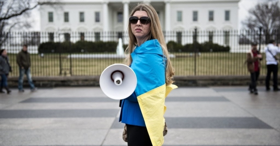 12.mar.2014 - Uma ativista se cobre com uma bandeira ucraniana do lado de for a da Casa Branca, durante uma manifestação contra o governo do presidente russo, Vladimir Putin, em Washington, durante o encontro entre o presidente dos EUA, Barack Obama, e o primeiro-ministro ucraniano, Arseniy Yatsenyuk