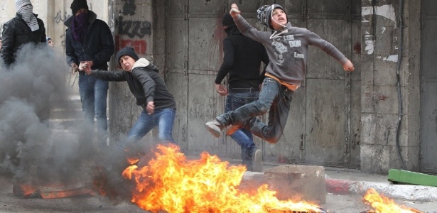 Garotos palestinos atiram pedras durante confronto com forças de segurança de Israel na cidade de Hebron, na Cisjordânia, em março - 17.mar.2014 - Hazem Bader/ AFP/ Topshots