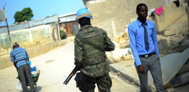 17.mar.2014 - Soldado da Minustah (missão da ONU no Haiti) caminha pela favela de Cité Soleil, em Porto Príncipe - Hector Retamal/AFP