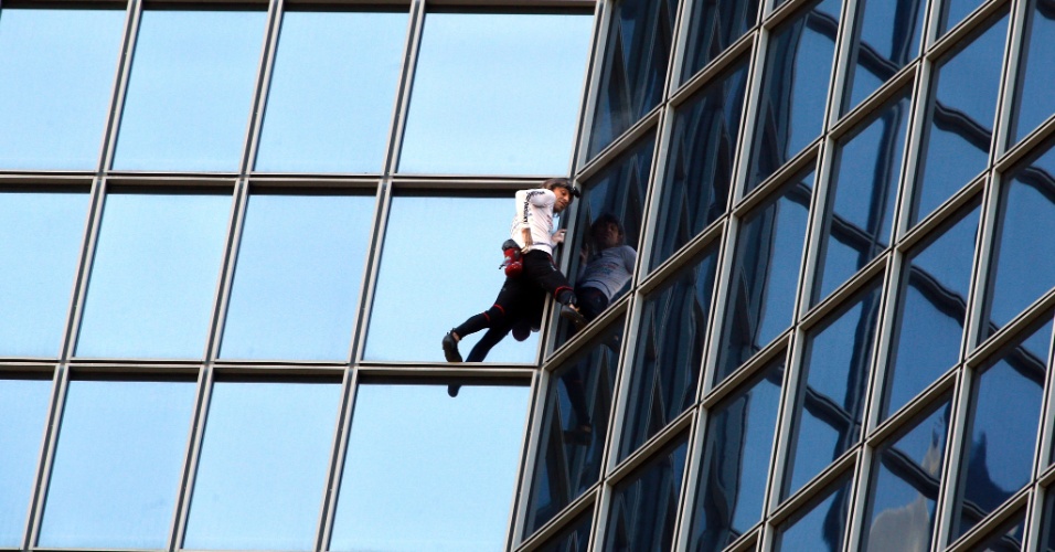 20.mar.2014 - Alain Robert, o escalador urbano francês apelidado de Homem-Aranha, sobe na sede da empresa Total, a 186 metros de altura, no bairro empresarial de La Defense, em Paris, na França
