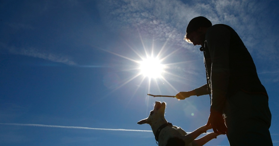 20.mar.2014 - Homem brinca com seu cão em um dia ensolarado de primavera no "Englischer Garten" em Munique, na Alemanha