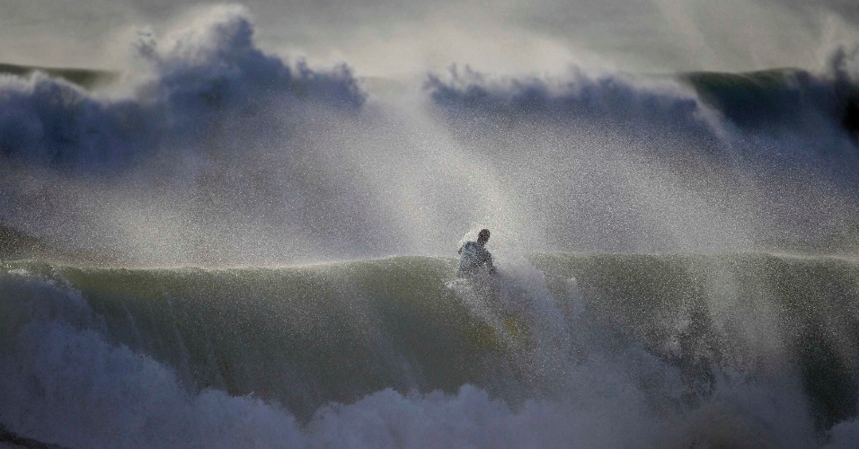 20.mar.2014 - Um bodyboarder entra no mar revolto durante competição na praia de Nazaré, em Portugal