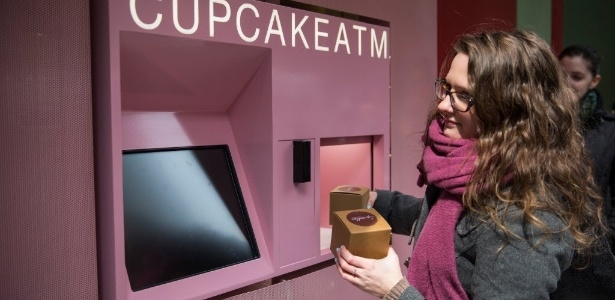 Mulher pega seu pedido de cupcakes depois de usar o "Cupcake ATM" em Nova York - Andrew Burton / Getty Images / AFP