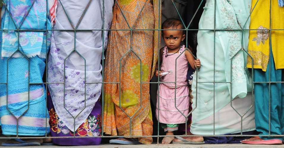 7.abr.2014 - Criança espera com eleitores do lado de fora de uma mesa de votação em Dibrugarh, na Índia