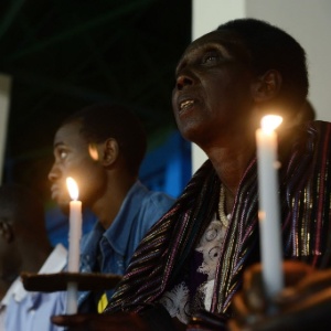 7.abr.2014 - Ruandeses seguram velas durante uma vigília noturna com orações para as vítimas do genocídio no estádio Amahoro, em Kigali - Simon Maina/ AFP
