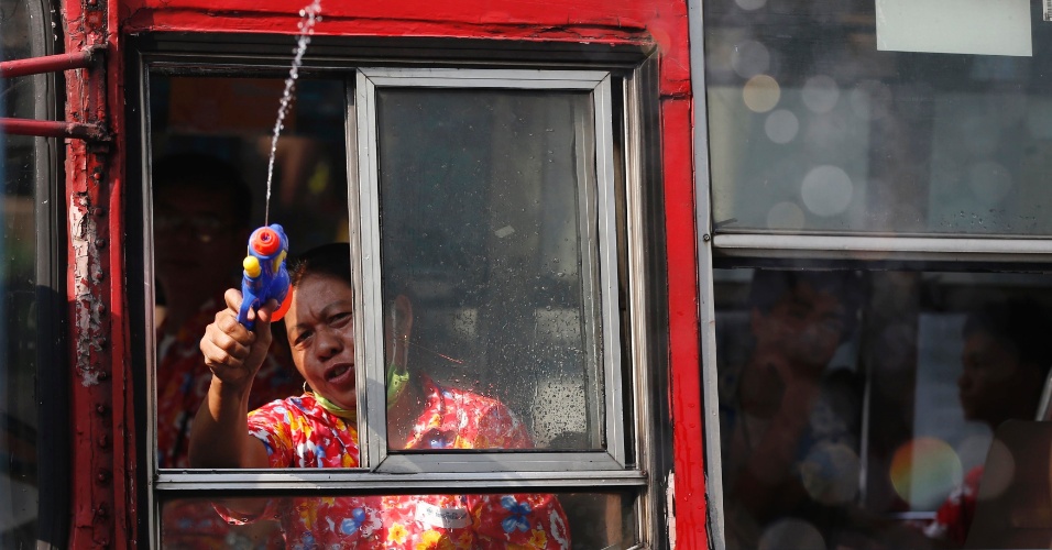 14.abr.2014 - Uma motorista lança água de um ônibus durante o festival Songkran, em Bancoc, nesta segunda-feira (14). A festividade, também conhecida como festival da Água, é celebrada tradicionalmente no país para marcar a chegada do Ano-Novo, normalmente entre os dias 13 de 15 de abril
