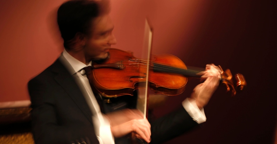 15.abr.2014 - Fotografia com baixa velocidade mostra o violinista David Aaron Carpenter interpretando o 'Macdonald' em um violino de Antonio Stradivari, feito em 1719, durante apresentação na casa de leilões Sotheby em Paris, na França