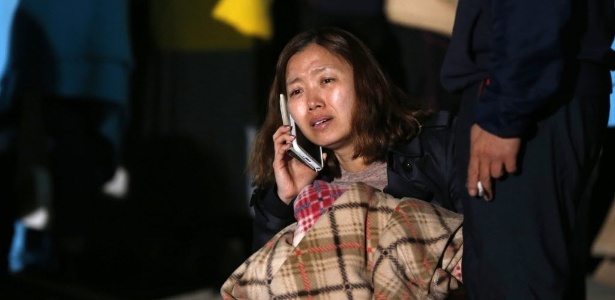Mulher chora ao telefone, enquanto espera juntamente com outros parentes de passageiros a balsa Sewol, por mais informações sobre sobreviventes - Kim Hong-Ji/Reuters