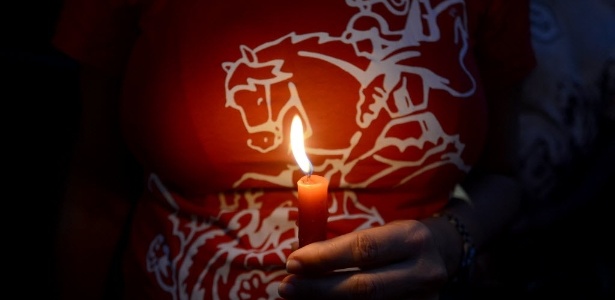 Devota de São Jorge veste camiseta com imagem em referência ao santo e carrega uma vela vermelha durante a celebração realizada na região central do Rio de Janeiro, que tem feriado no dia de São Jorge - Lucas Landau/UOL