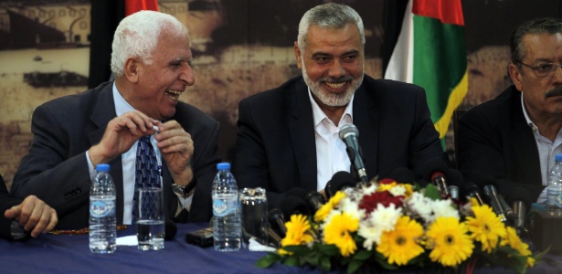 O chefe da delegação palestina, Azzam al-Ahmed (à esq.), sorri com o primeiro-ministro do Hamas na faixa de Gaza, Ismail Haniya (centro), durante entrevista em Gaza, nesta quarta-feira (23). O líderes rivais da Cisjordânia e da faixa de Gaza concordaram em formar um governo de unidade dentro de cinco semanas, em meio ao colapso das negociações de paz com Israel - Said Khatib/AFP