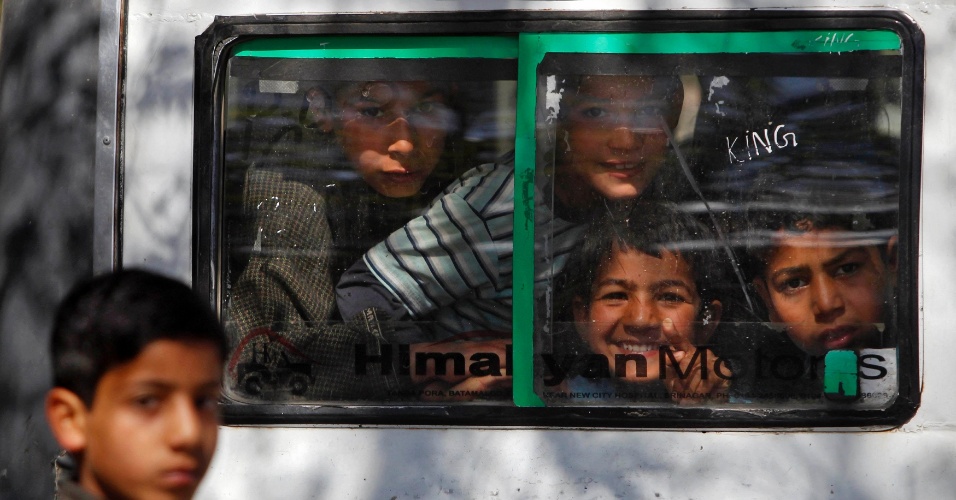 24.abr.2014 - Crianças acenam através da janela de um trem, durante viagem em Merhama, na Índia