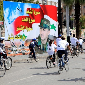 O presidente da Síria Bashar Assad (na foto no cartaz) pode sair fortalecido da guerra dos EUA com o Estado Islâmico - AFP