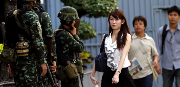 Pedestre passa por soldados tailandeses em frente ao edifício Shinawatra 2, sobrenome da primeira-ministra deposta pelo Exército - Narong Sangnak/Efe