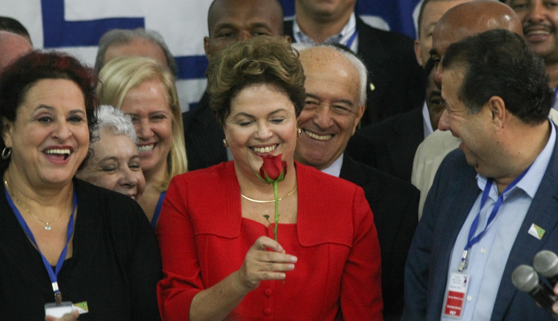 10.jun.2014 - Ao lado de Carlos Lupi, presidente nacional do PDT (dir.), a presidente Dilma Rousseff olha rosa, que faz parte do símbolo do partido, durante convenção nacional da sigla. O PDT oficializou apoio à reeleição da presidente. Na votação, nenhum convencional levantou o crachá quando questionado quem era contra a aliança com a presidente - Joel Rodrigues/Folhapress