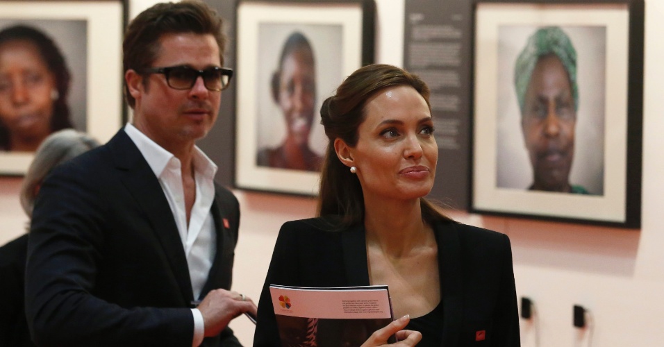 12.jun.2014 - Os atores Angelina Jolie e Brad Pitt observam fotografias em evento à margem da cúpula pelo fim da violência sexual em zonas de conflito no Centro Excel, em Londres, nesta quinta-feira (12)