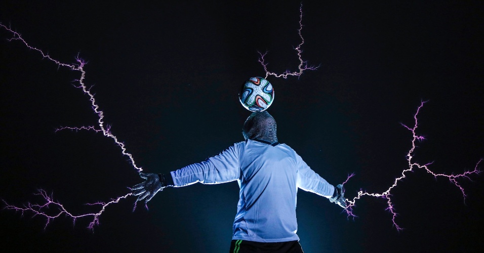 17.jun.2014 - Membro da banda Thunderbolt Craziness vestindo um terno de metal equilibra uma bola de futebol na cabeça com uma descarga de eletricidade a partir de bobinas de Tesla, durante uma performance para comemorar a Copa do Brasil de 2014, em Changle, na província de Fujian, na China