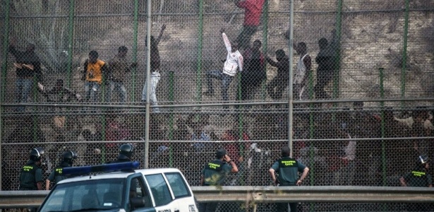 18.jun.2014 - Imigrantes tentam escalar grade que separa o Marrocos do enclave espanhol no país, na cidade de Melilla - José Colon/AFP