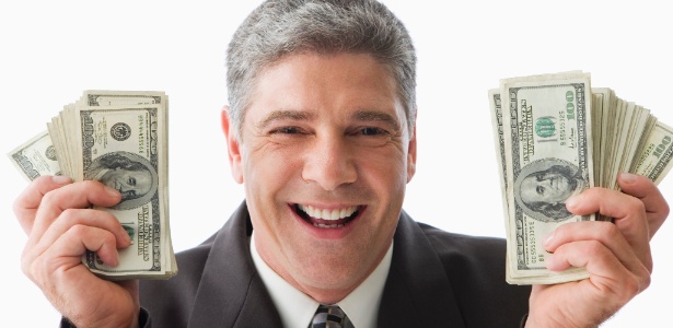 homem segura muito dólar - Getty Images - Getty Images