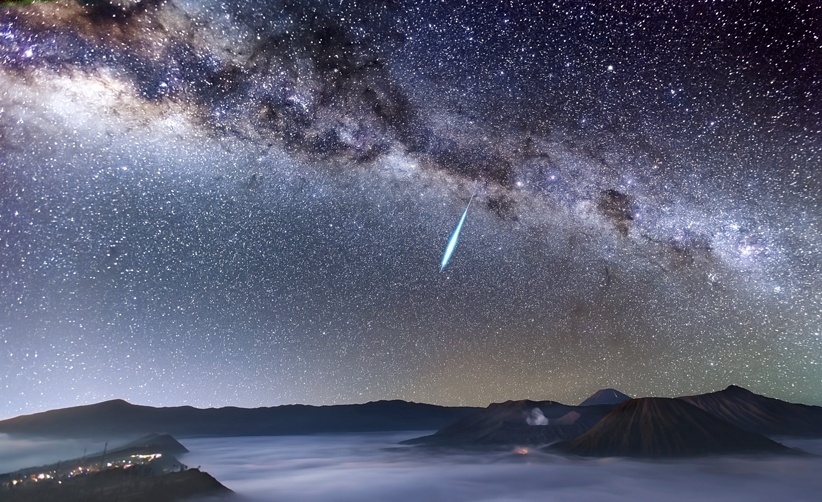 3.jul.2014 - Um meteoro brilhante rasga o céu sobre sobre o monte Bromo, que solta fumaça na Indonésia