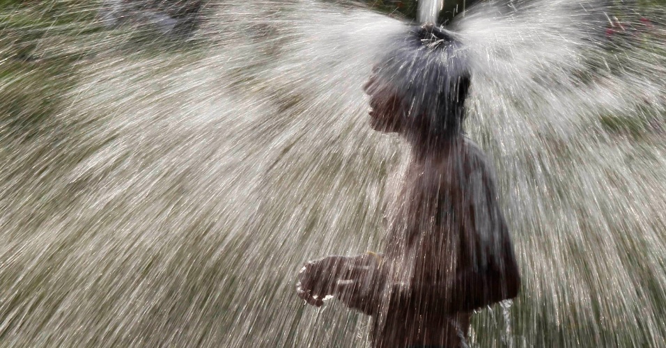 9.jul.2014 - Homem toma banho nas águas de um tubo pela manhã na vila Salamatpur, em Punjab, na Índia