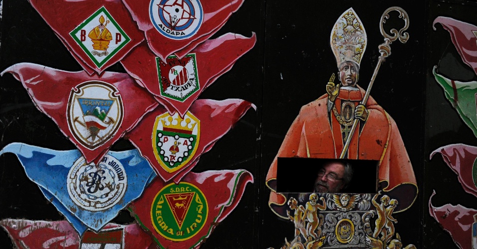 10.jul.2014 - Homem observa abertura em uma parede com uma imagem representando São Firmino, durante o festival em Pamplona, na Espanha