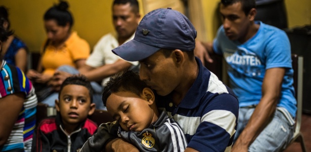 Homem espera com seus dois filhos por um ônibus que sairá de San Pedro Sula, em Honduras, cidade com alto índice de assassinatos de crianças e adolescentes, a maioria atribuída à ação de gangues - Meridith Kohut/The New York Times