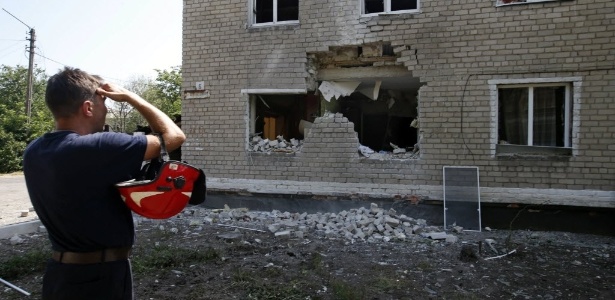 Funcionário do serviço de emergência observa edifício atingido por bombardeio de forças ucranianas, em Maryinka, região de Donetsk