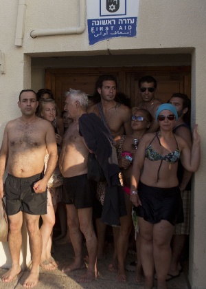 Israelenses e turistas se escondem em banheiro de praia de Tel Aviv durante um ataque de foguete, feito por militantes palestinos da faixa de Gaza - Ahmad Gharabli/AFP