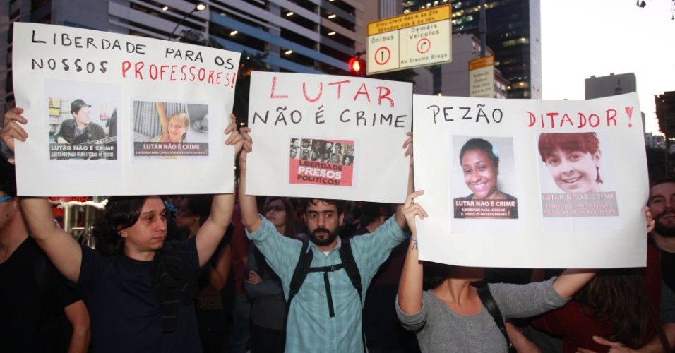 15.jul.2014 - Manifestantes erguem cartazes durante protesto contra a prisão de ativistas envolvidos com manifestações na véspera da final da Copa do Mundo. O protesto acontece em frente ao Tribunal de Justiça do Rio de Janeiro, no centro da capital fluminense, nesta terça-feira (15)