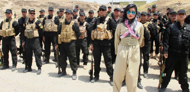 15.jul.2014 - A cantora curda Helly Luv posa na frente de uma tropa curda armada em uma base em Dohuk, no Iraque