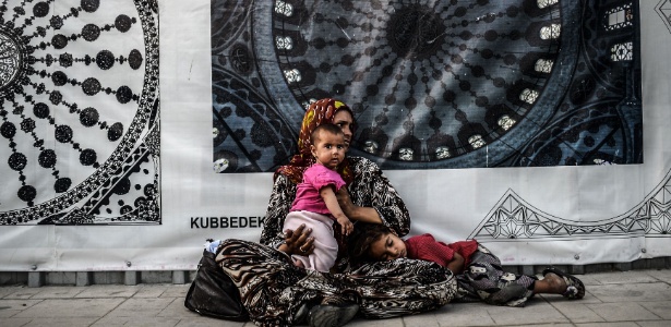 Mulher síria pede esmolas com os filhos no centro da cidade de Istambul, na Turquia, país que tem recebido dezenas de milhares de refugiados sírios em sua capital - Bulent Kilic/AFP
