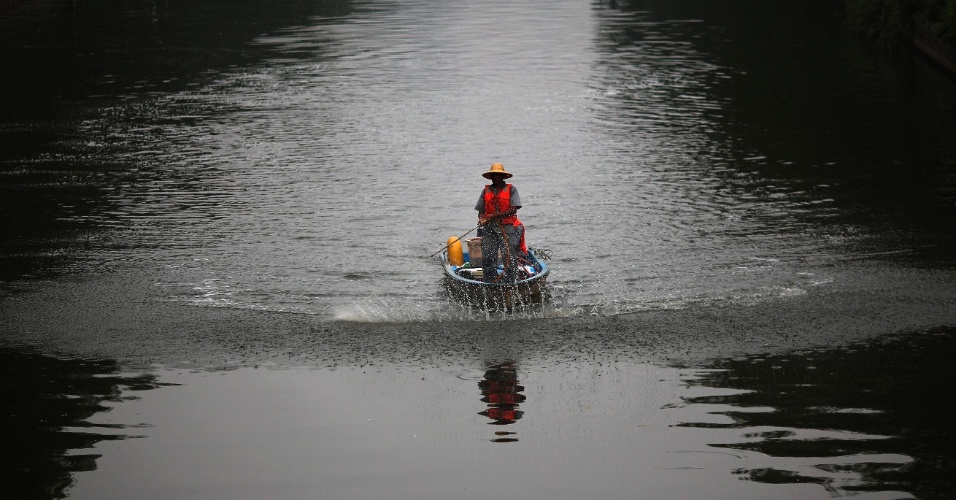 17.jul.2014 - Um trabalhador em um barco com um spray clarificador de água, em um canal poluído em Pequim, na China