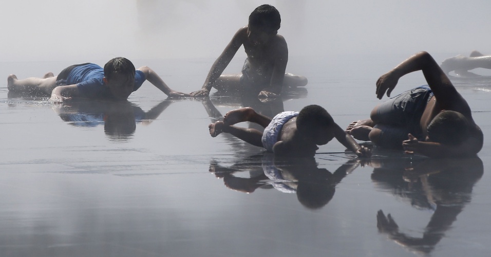 18.jul.2014 - Crianças brincam na água de uma fonte em um dia quente de verão em Nice, na França