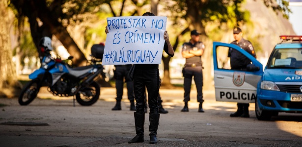 Manifestante ergue cartaz em frente ao consulado do Uruguai, no Botafogo, zona sul do Rio de Janeiro, na segunda-feira (21) - Daniel Marenco/Folhapress